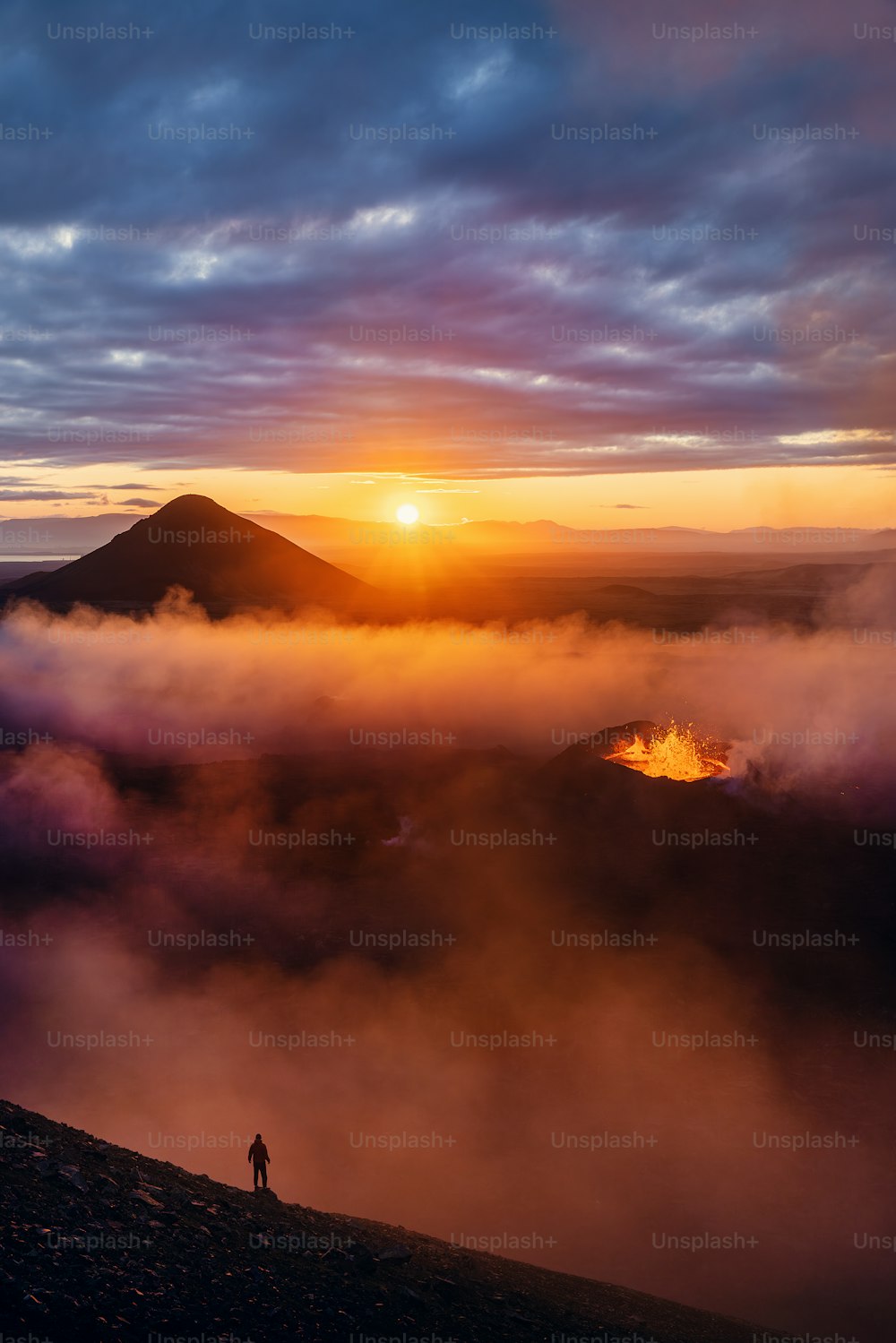 a person standing on top of a mountain with a sunset in the background