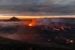 a volcano spewing out lava at sunset