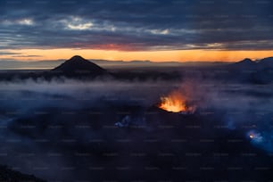 the sun is setting over the mountains and clouds