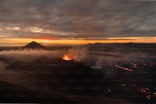 Un vulcano che vomita lava al tramonto