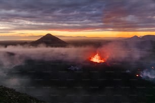 a volcano spewing out lava in the middle of a valley