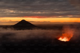 a volcano spewing out lava at sunset