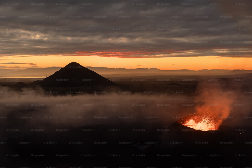 um vulcão expelindo lava ao pôr do sol