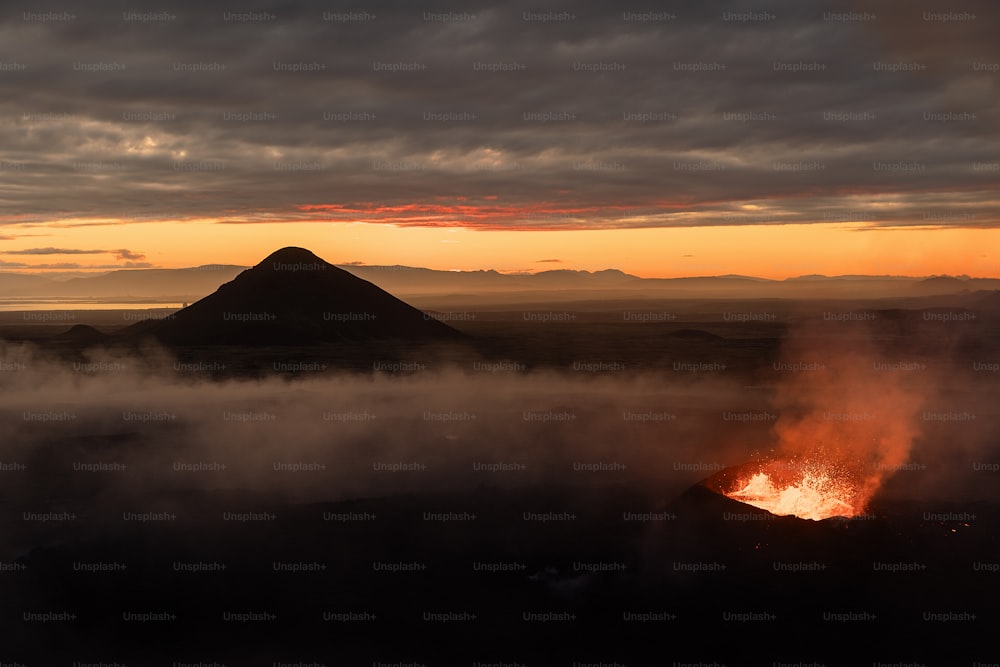 a volcano spewing out lava at sunset