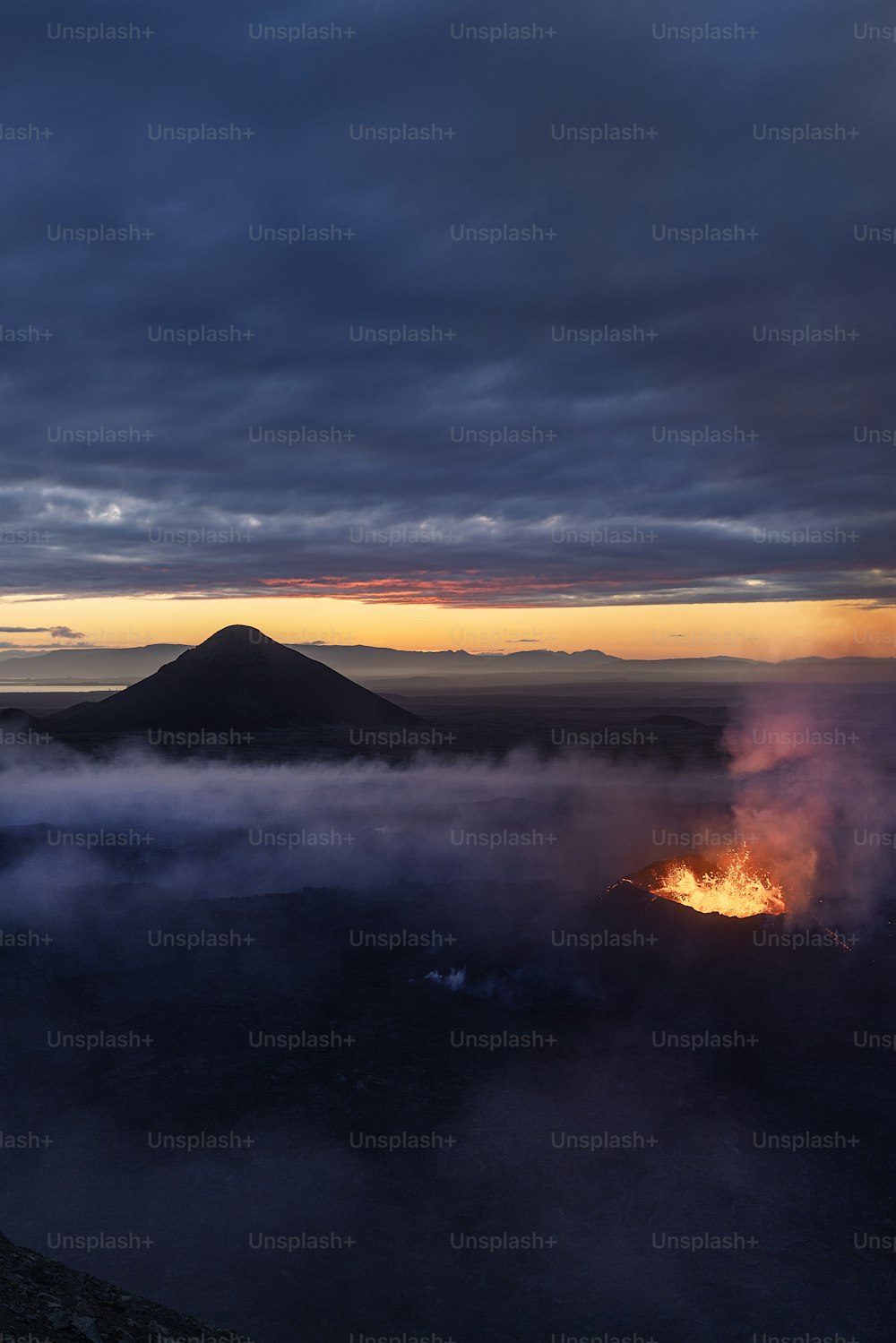 a volcano spewing out lava in the distance