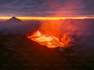 Un vulcano erutta lava mentre il sole tramonta