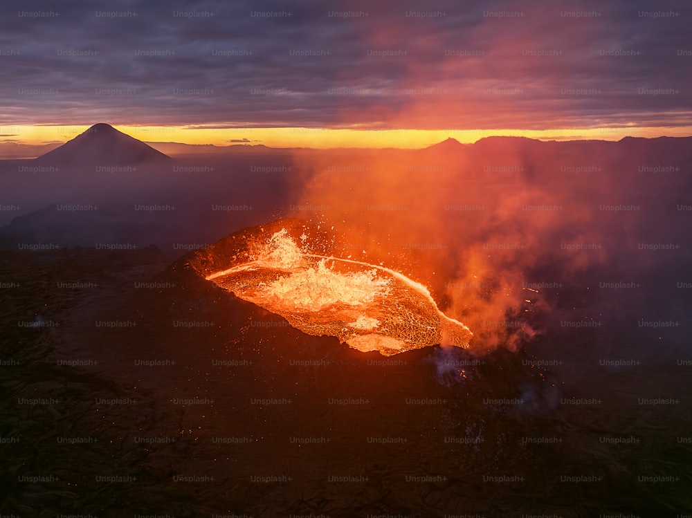 a volcano erupts lava as the sun sets
