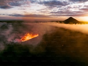 a volcano spewing out lava at sunset