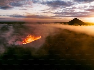 Un volcan crachant de la lave au coucher du soleil