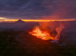 Um vulcão entra em erupção com lava quando o sol se põe