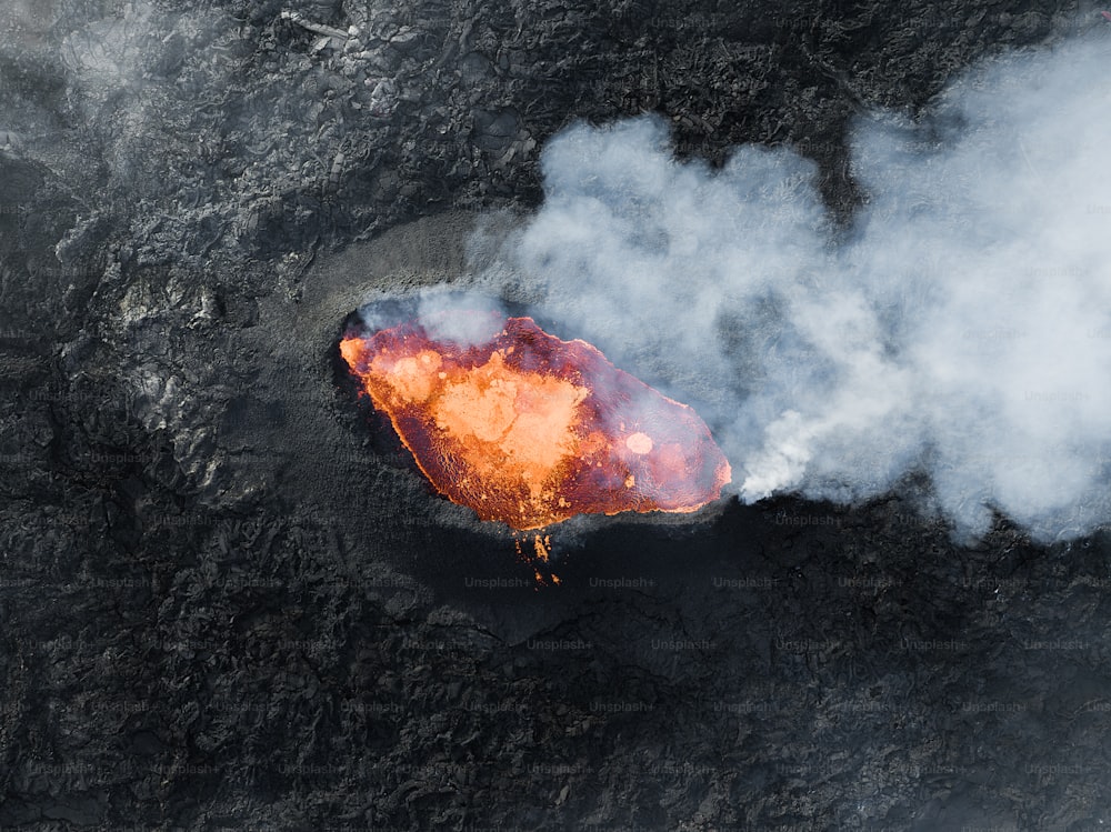 an aerial view of a volcano with smoke coming out of it