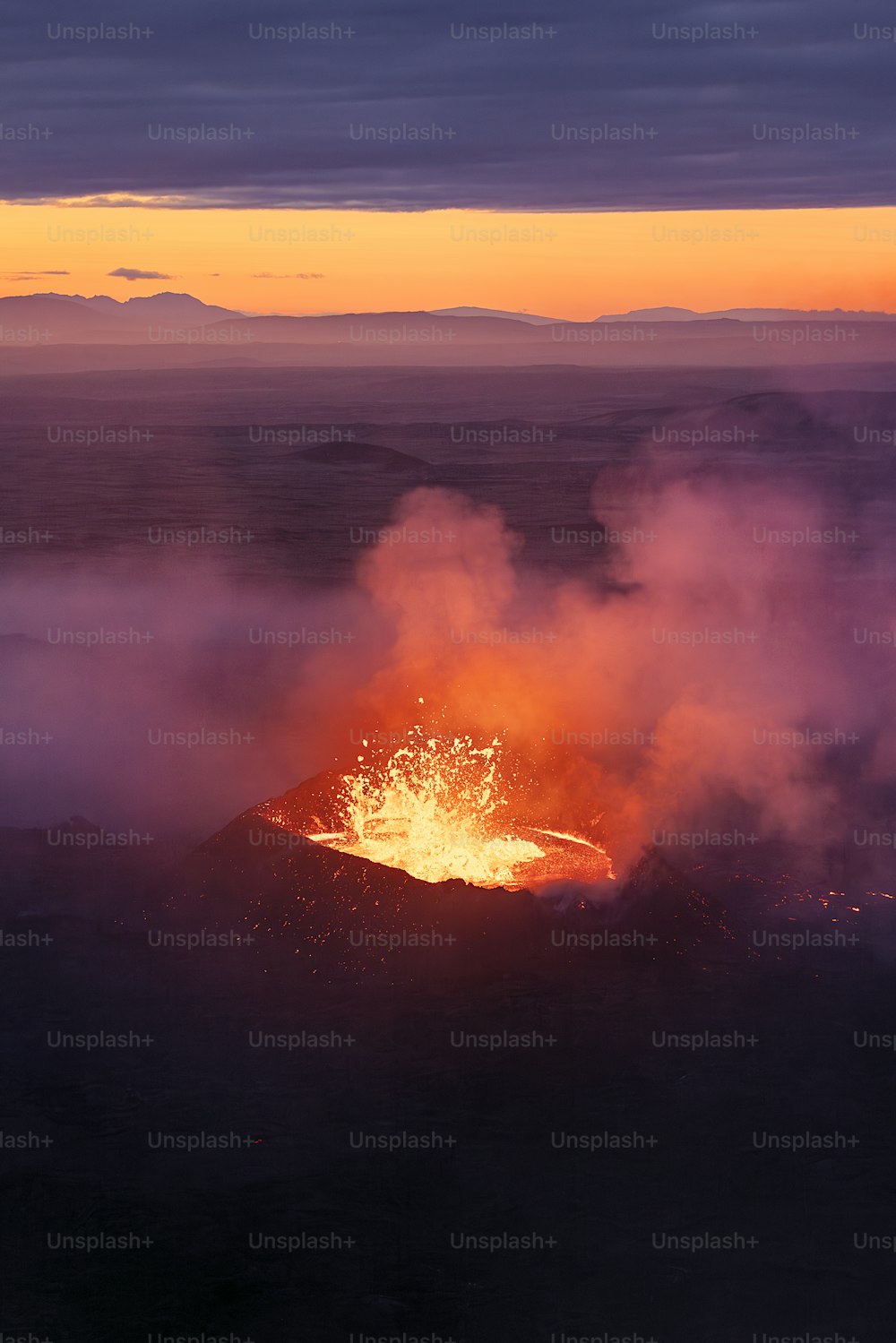 a volcano spewing out lava at sunset