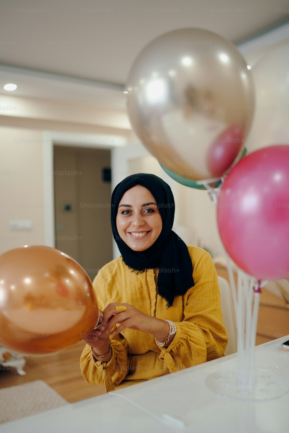 a woman in a hijab is holding balloons