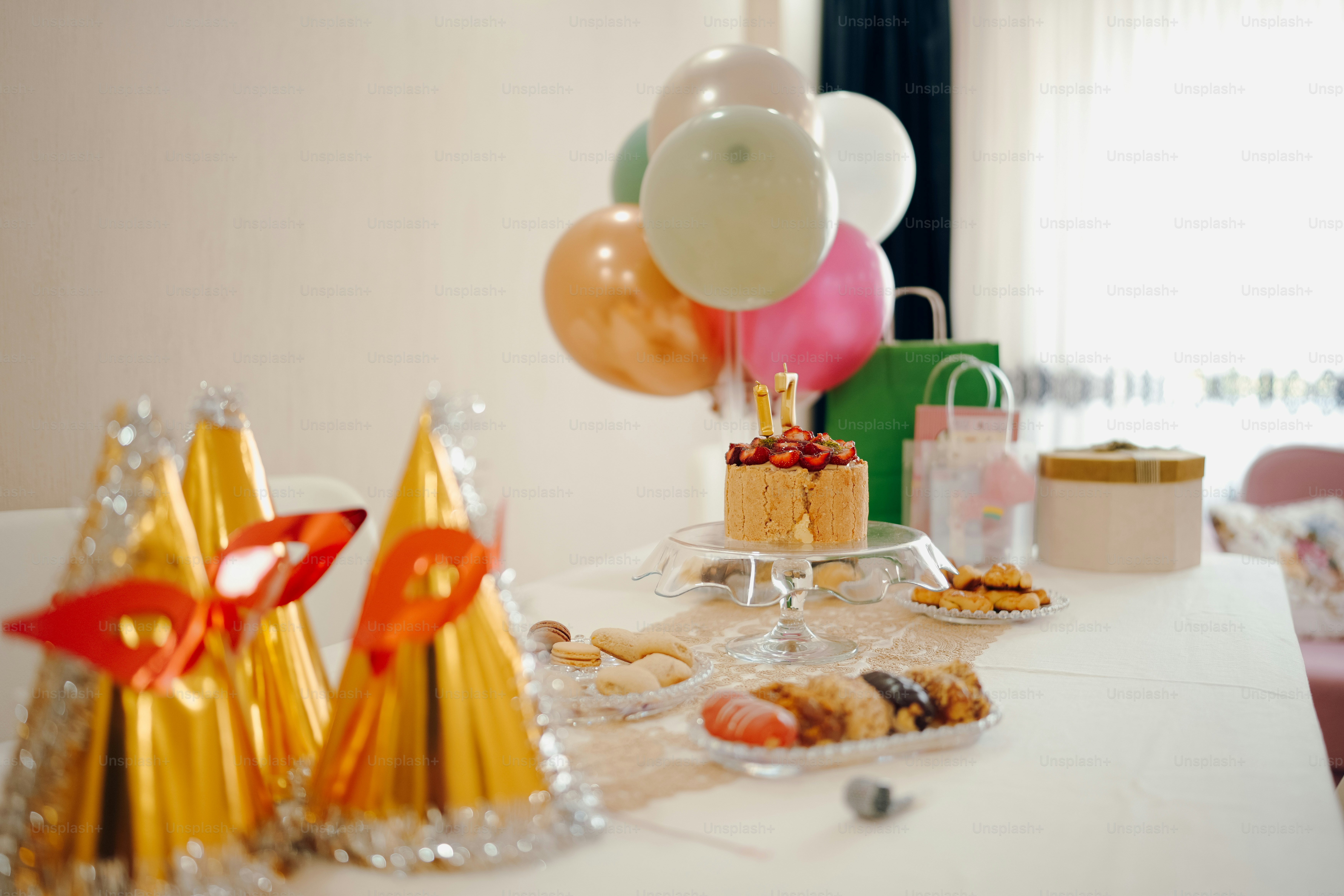 a table topped with a cake and lots of balloons
