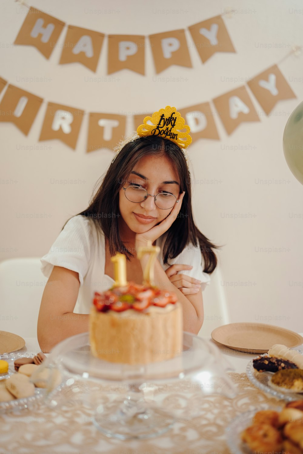 a girl sitting at a table with a birthday cake