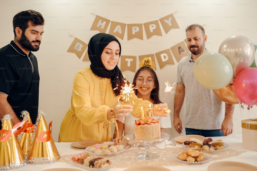 a group of people standing around a table with a cake
