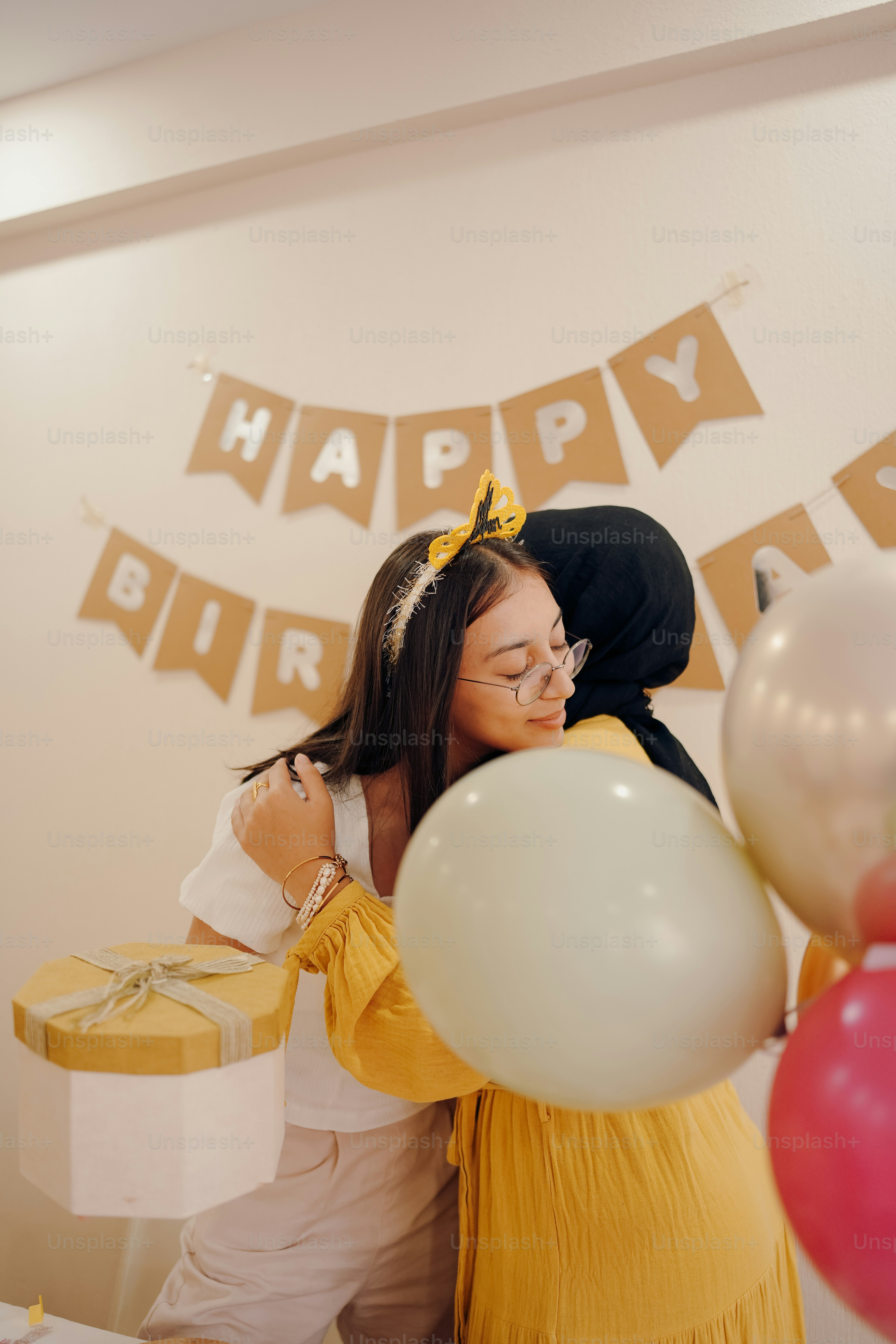 two women hugging each other in front of a birthday banner