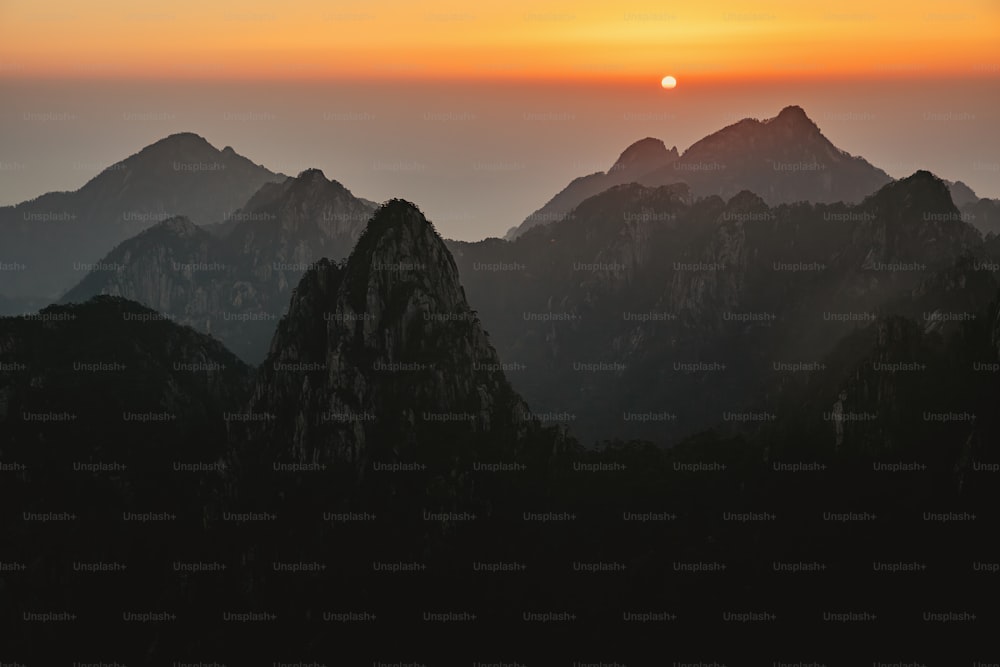 the sun is setting over a mountain range