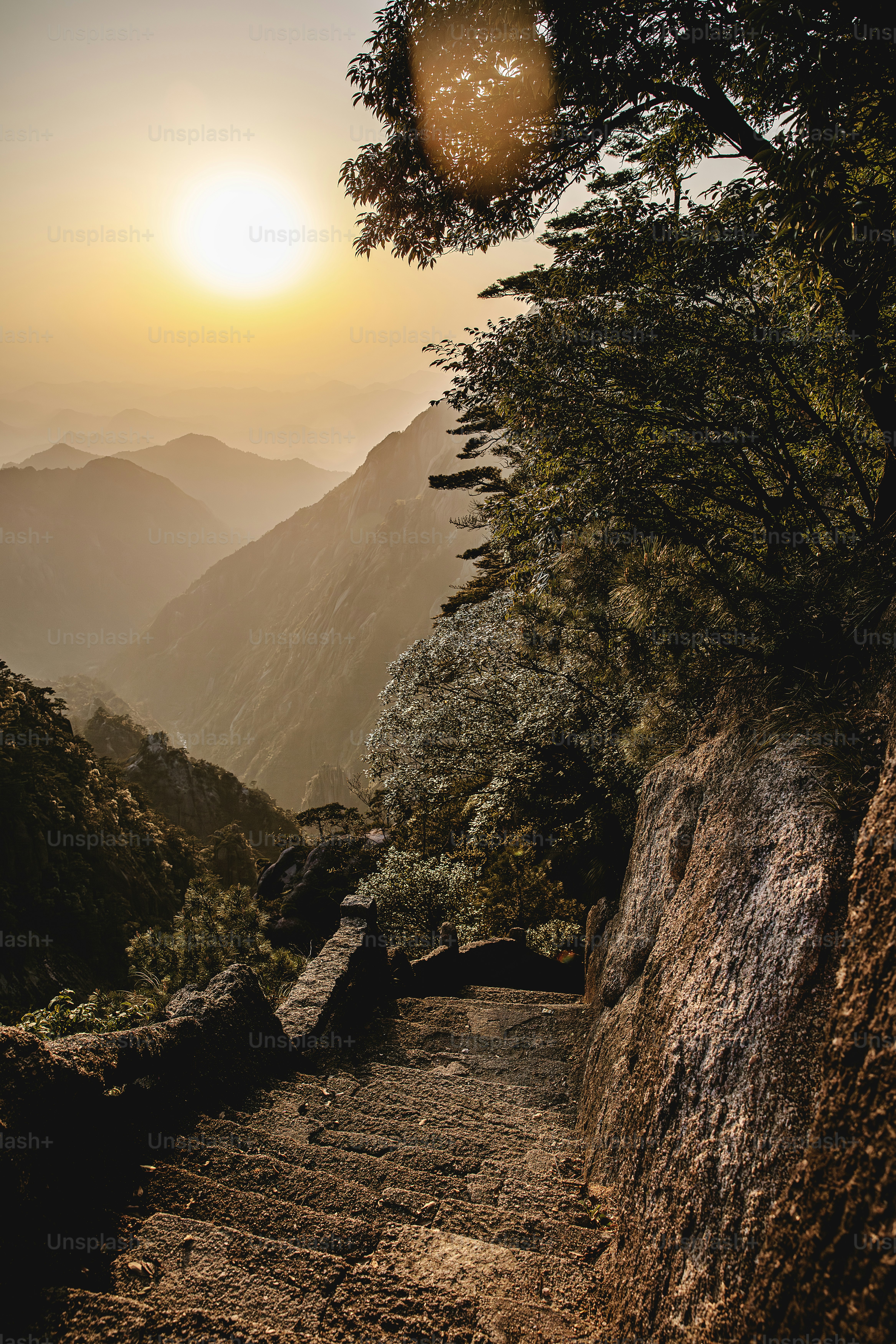 the sun is setting over the mountains and trees