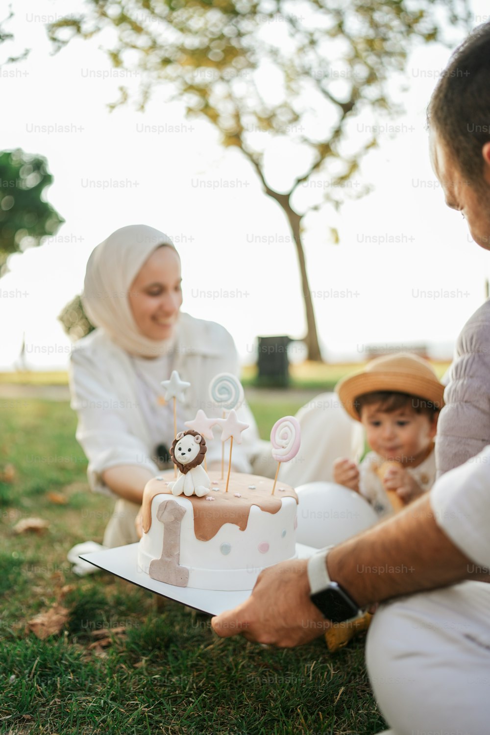 a man and a woman sitting on the grass with a cake