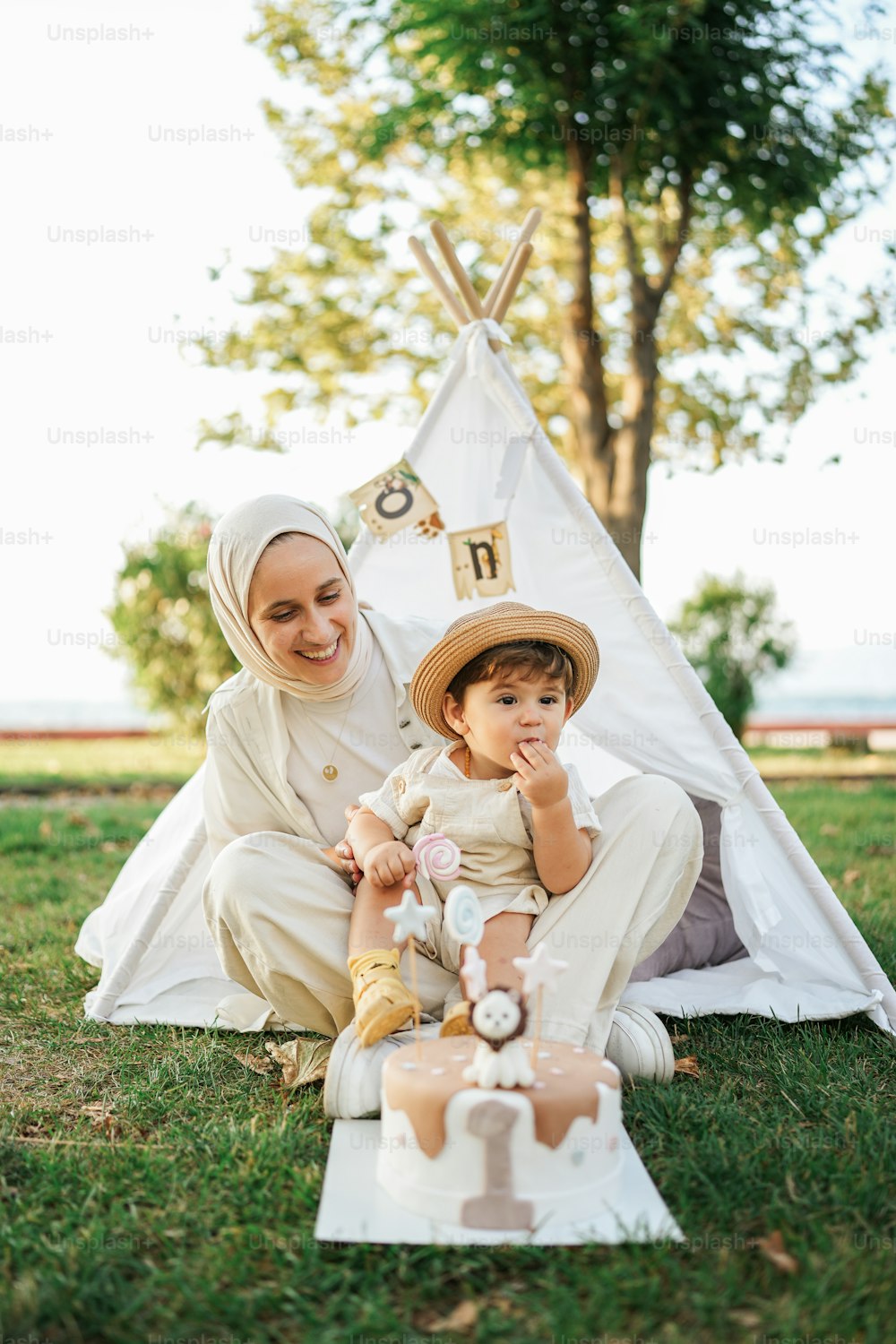 a woman and a baby sitting in front of a teepee