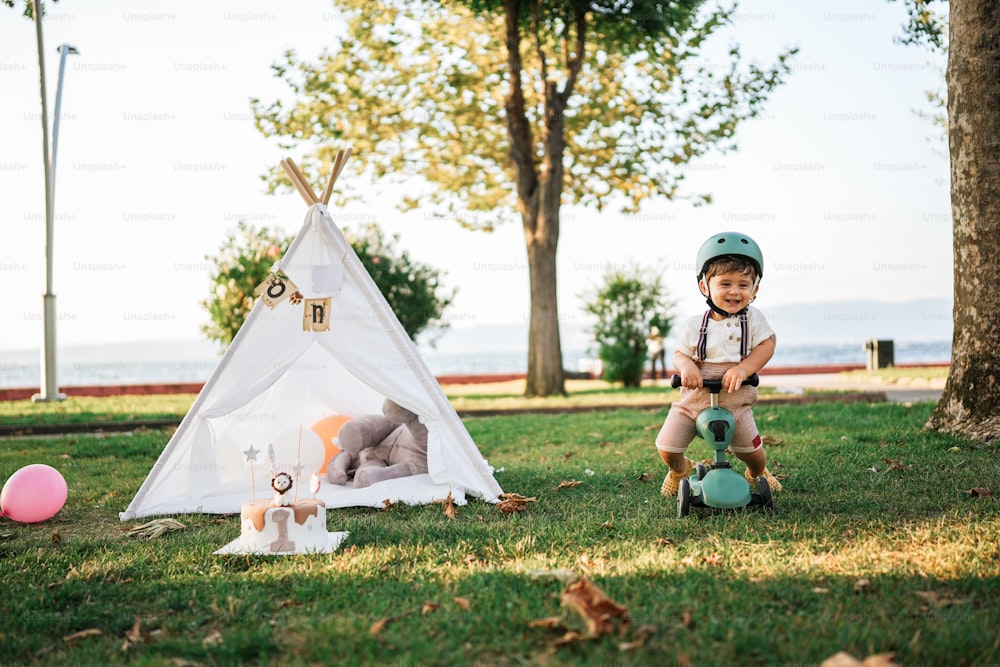 a little boy sitting on a tricycle next to a teepee tent
