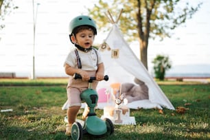 a little boy riding a scooter in the grass