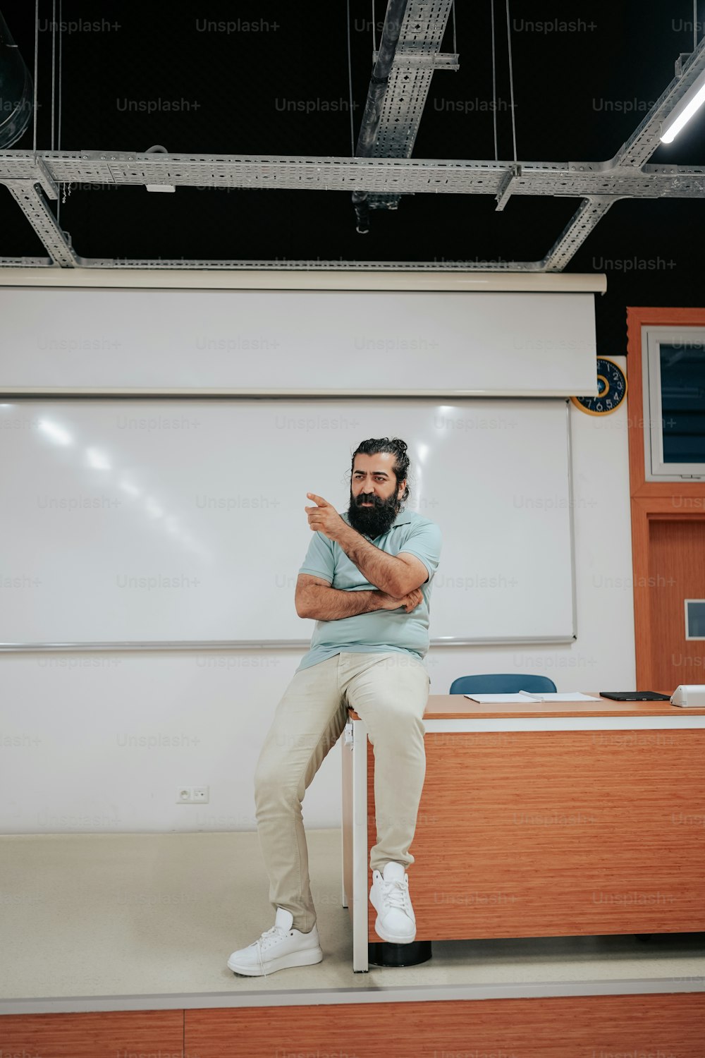 a man with a beard sitting in front of a whiteboard