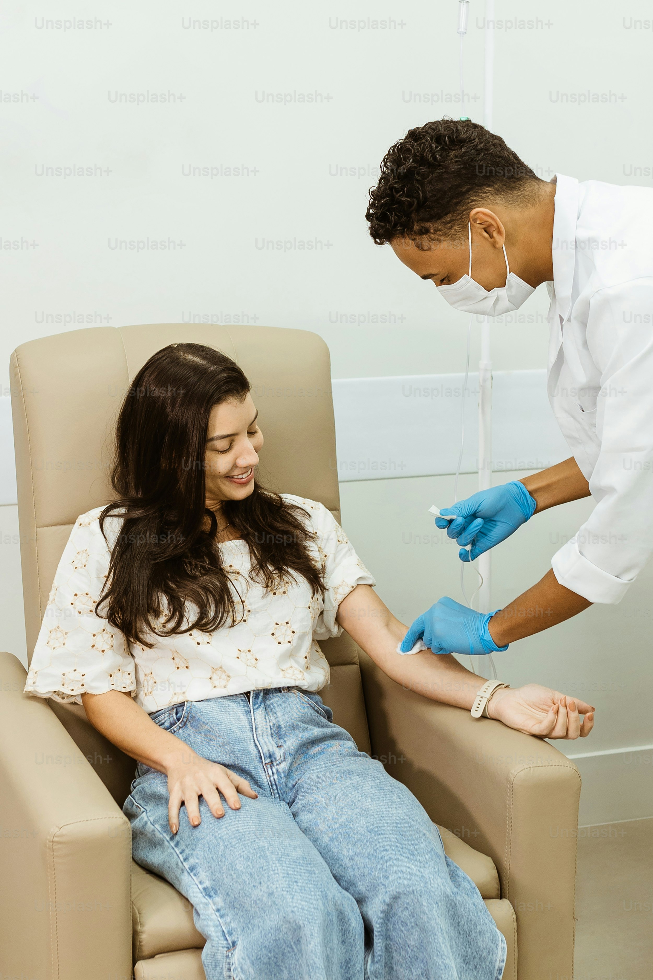 a woman sitting in a chair with a man in a white shirt and blue gloves