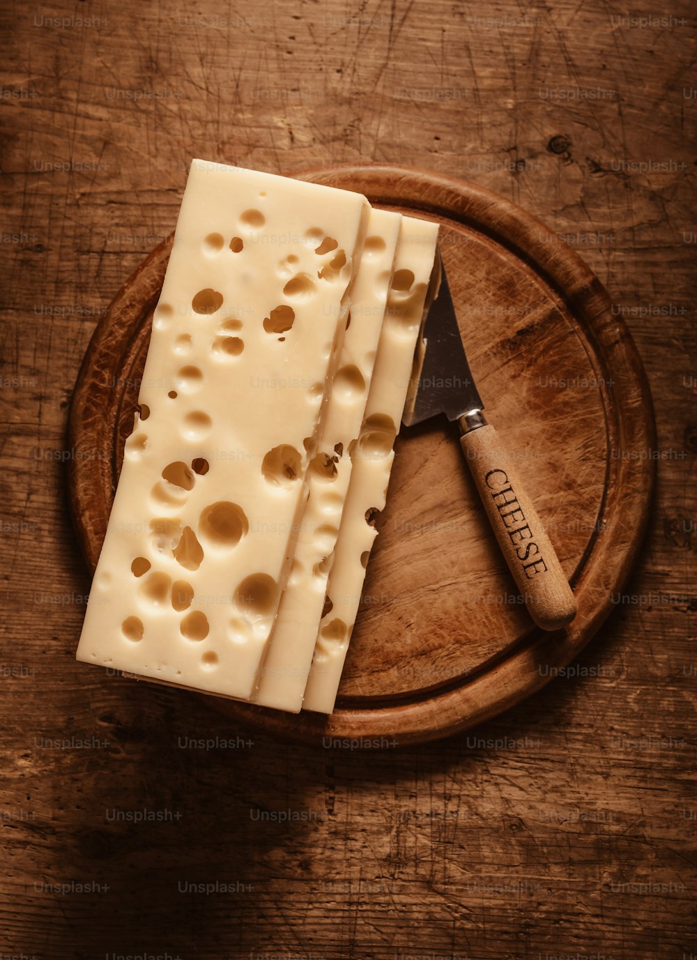 a piece of cheese on a wooden plate with a knife