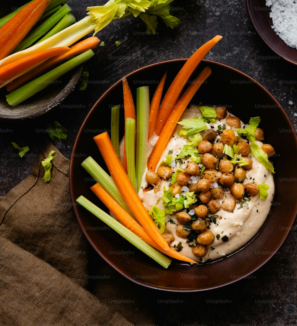 a bowl filled with carrots, celery and chickpeas
