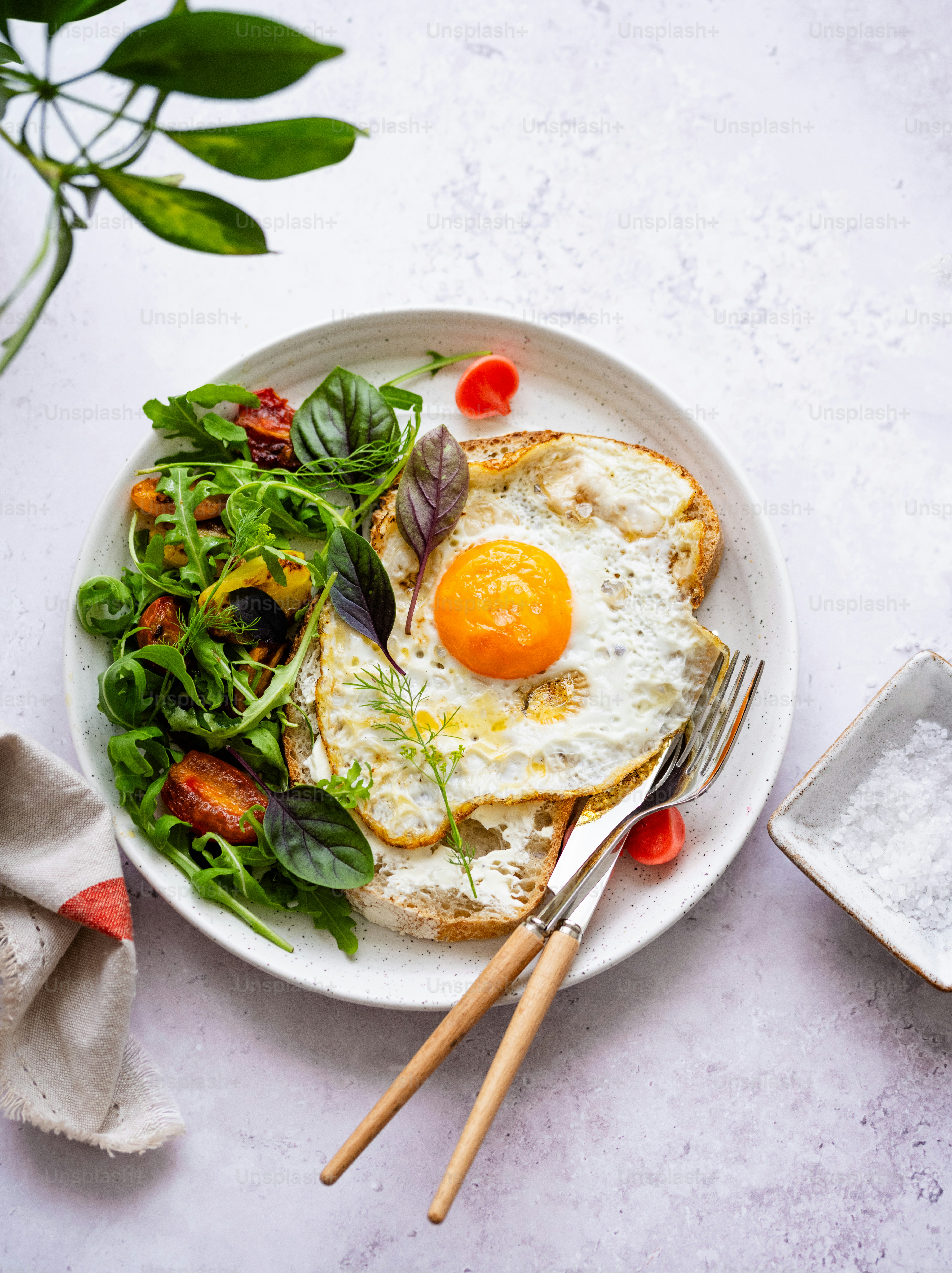 a white plate topped with a fried egg next to a salad