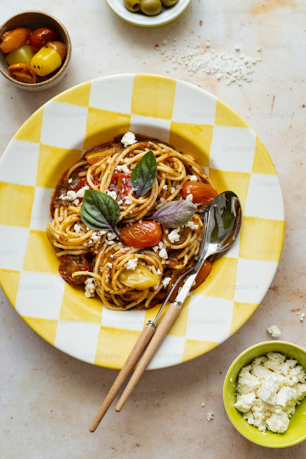 a plate of spaghetti with tomatoes and feta cheese