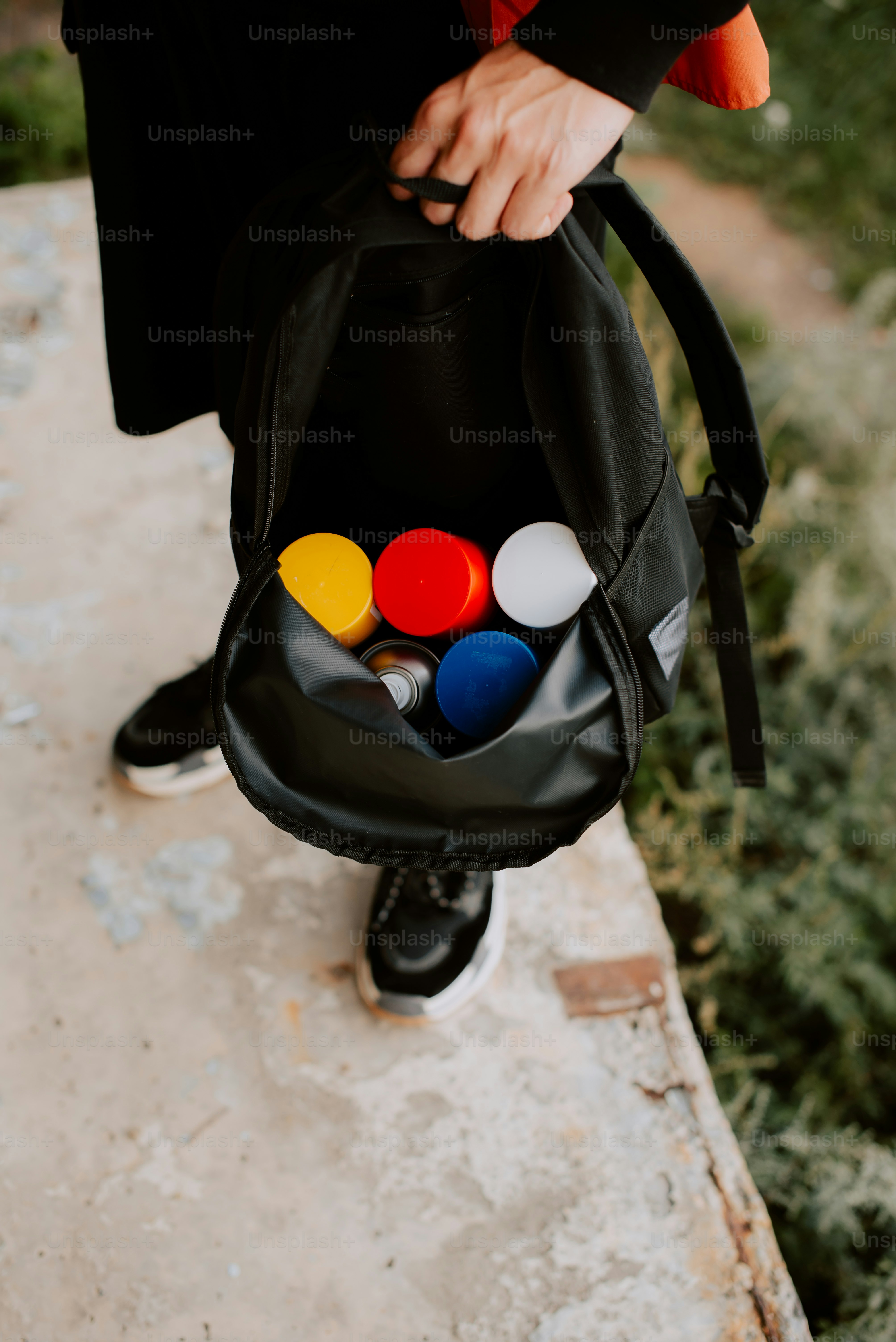 a person holding a black bag filled with different colored objects