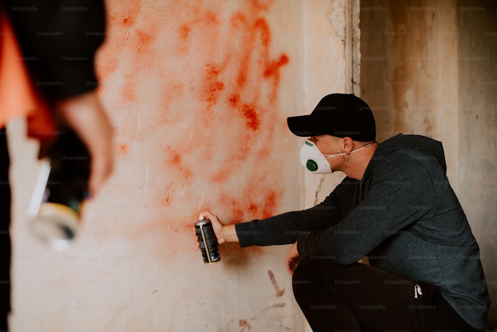 a man is painting a wall with red paint