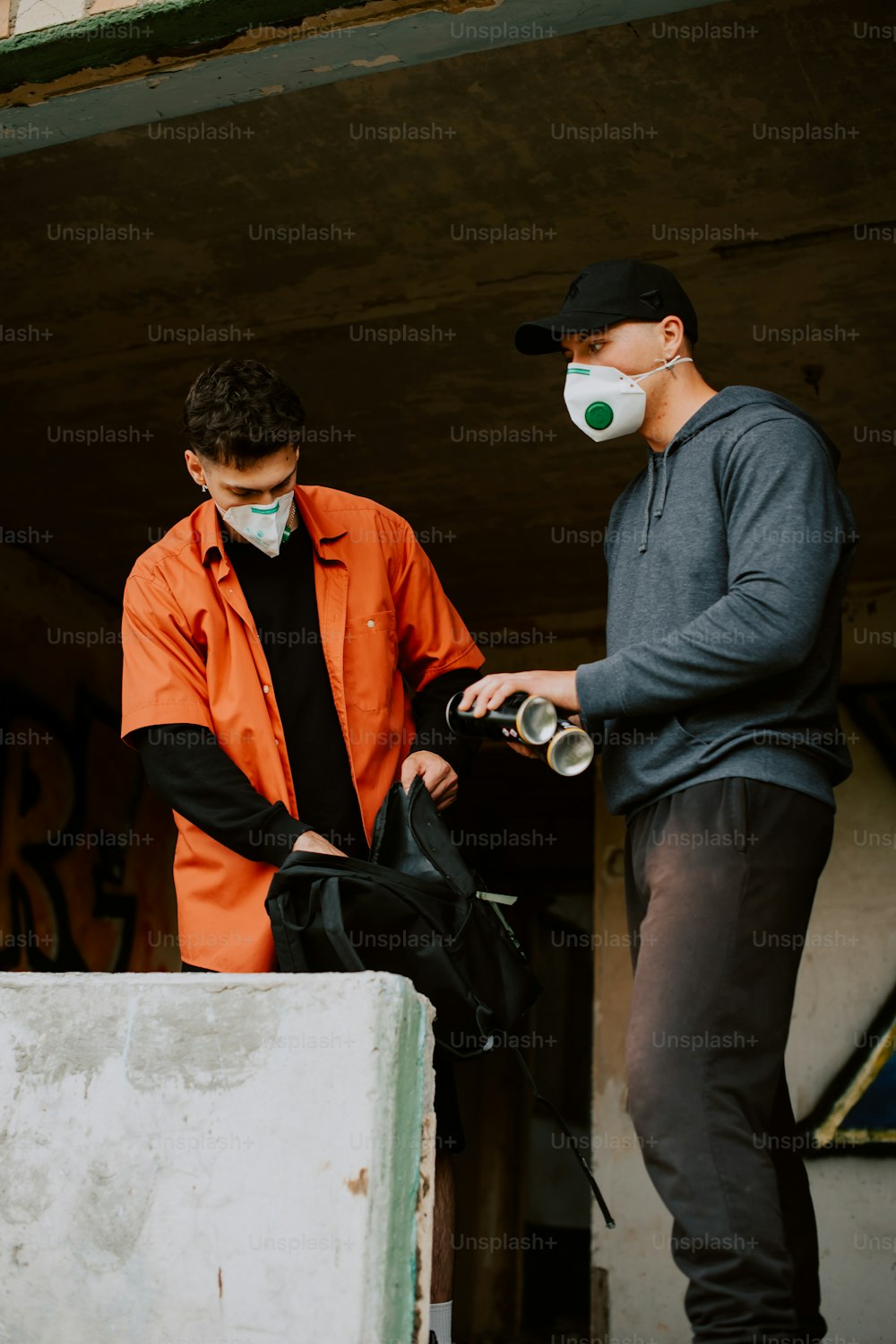 two men in orange shirts and black pants with masks on