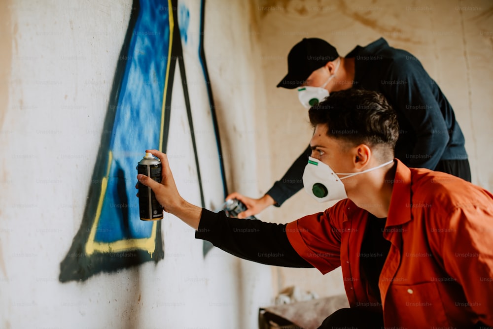 two men are painting on a wall