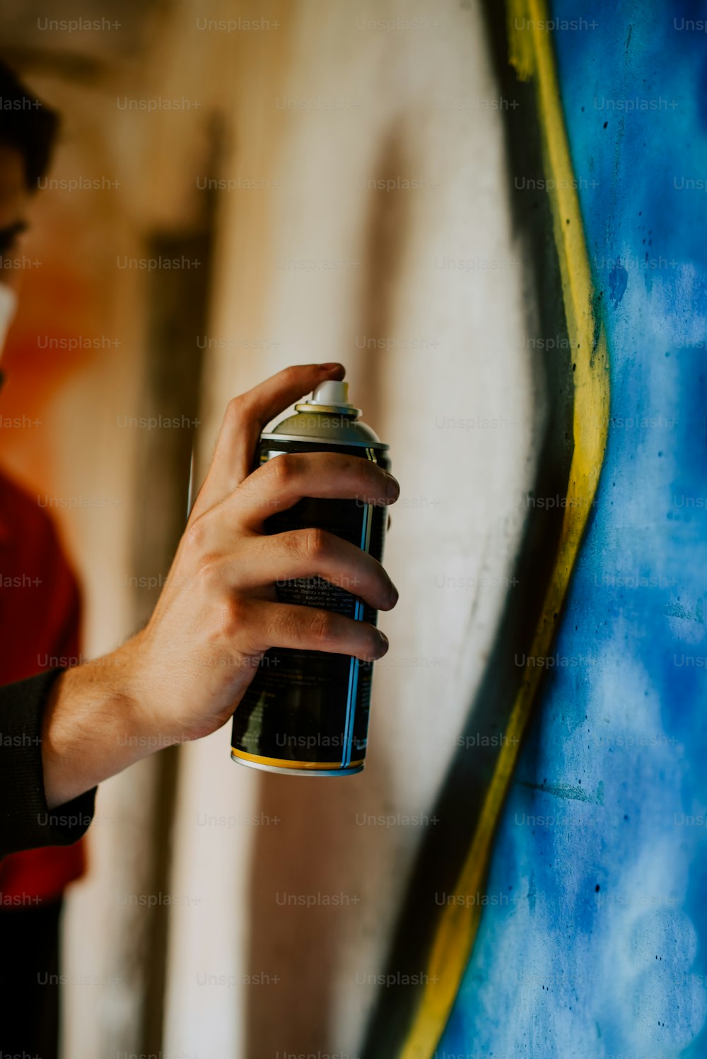 a person holding a can of paint in front of a wall