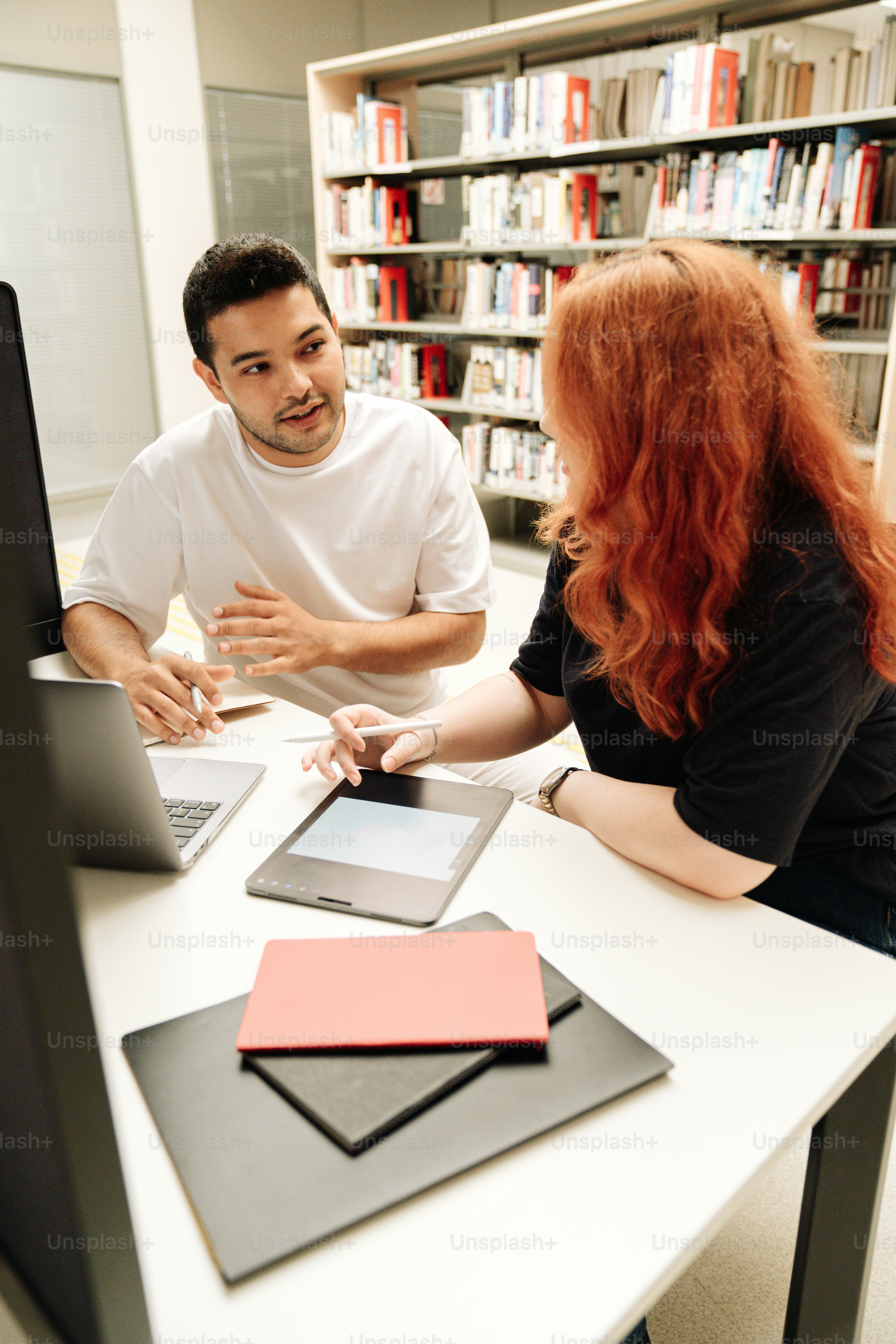 コンピューターの前のテーブルに座っている男女