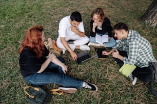 a group of people sitting on the ground with laptops
