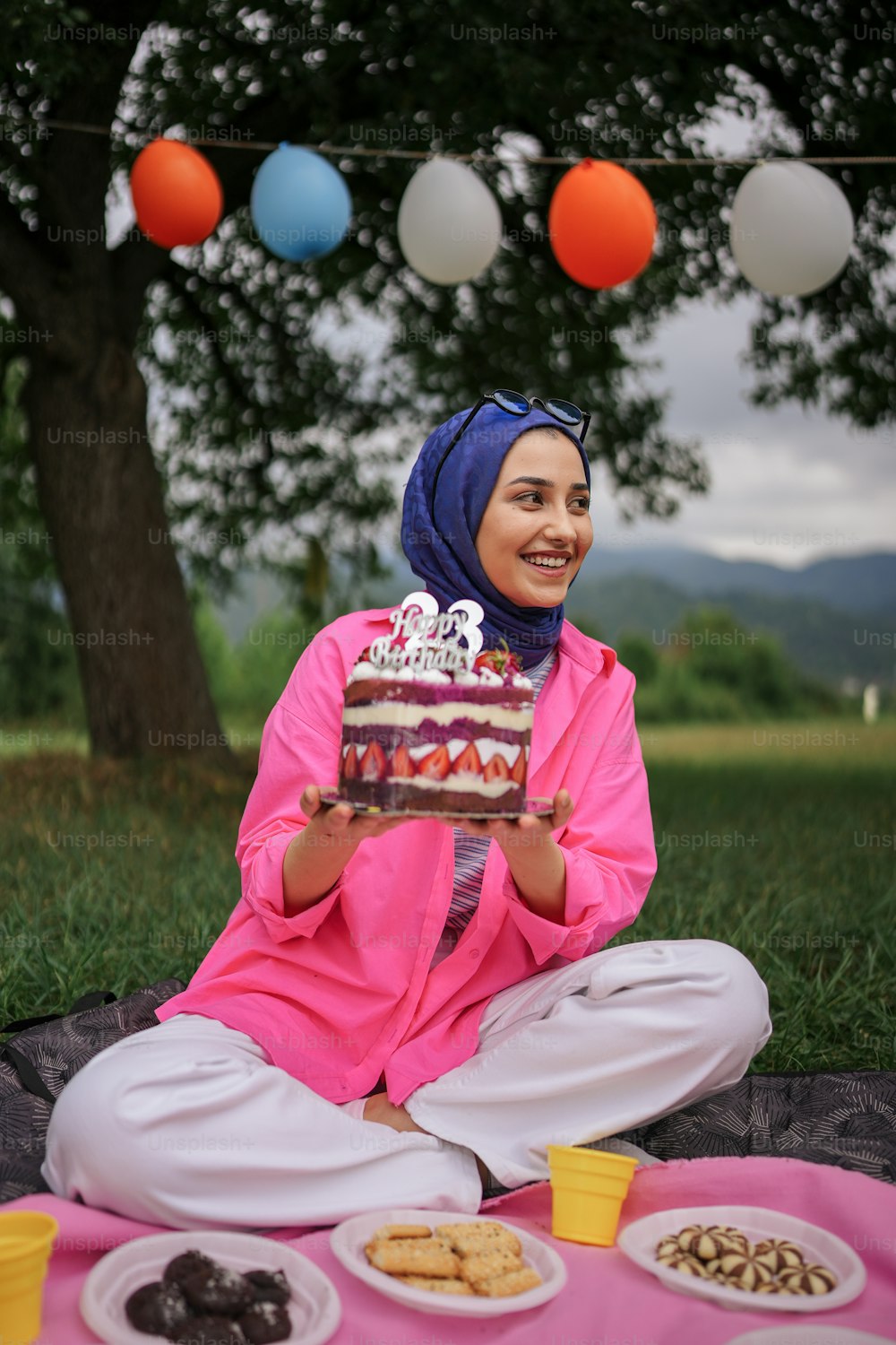 a woman sitting on a blanket holding a piece of cake