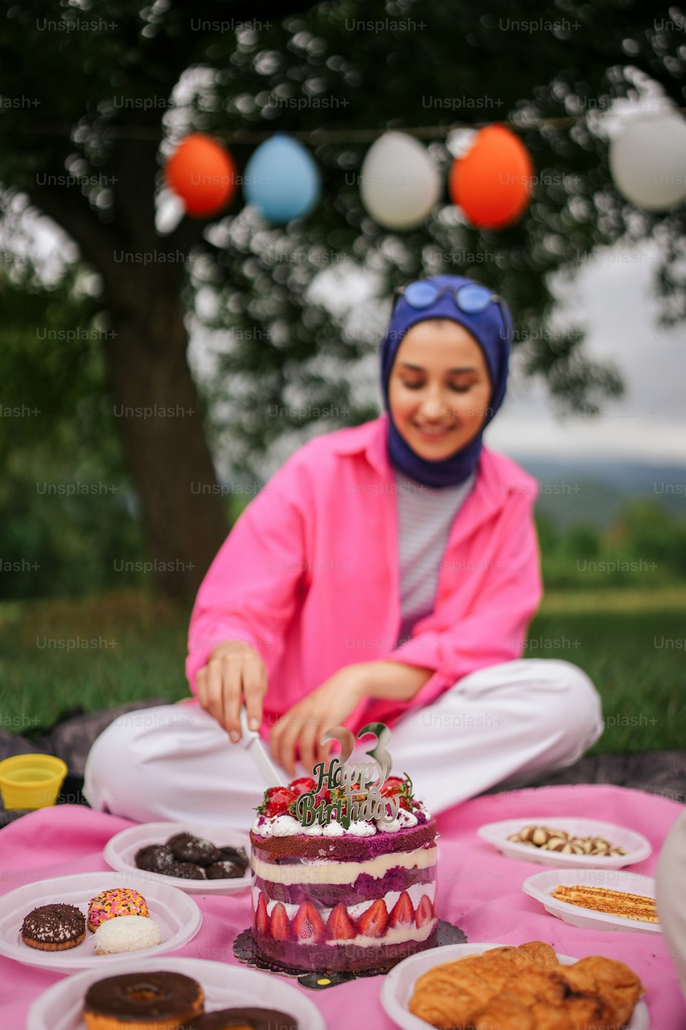 a woman sitting on the ground cutting a cake
