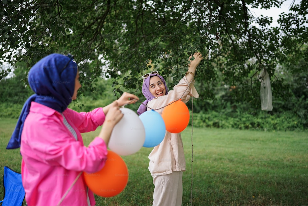 Un par de mujeres de pie una al lado de la otra sosteniendo globos