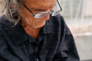 a man wearing glasses looking down at his cell phone