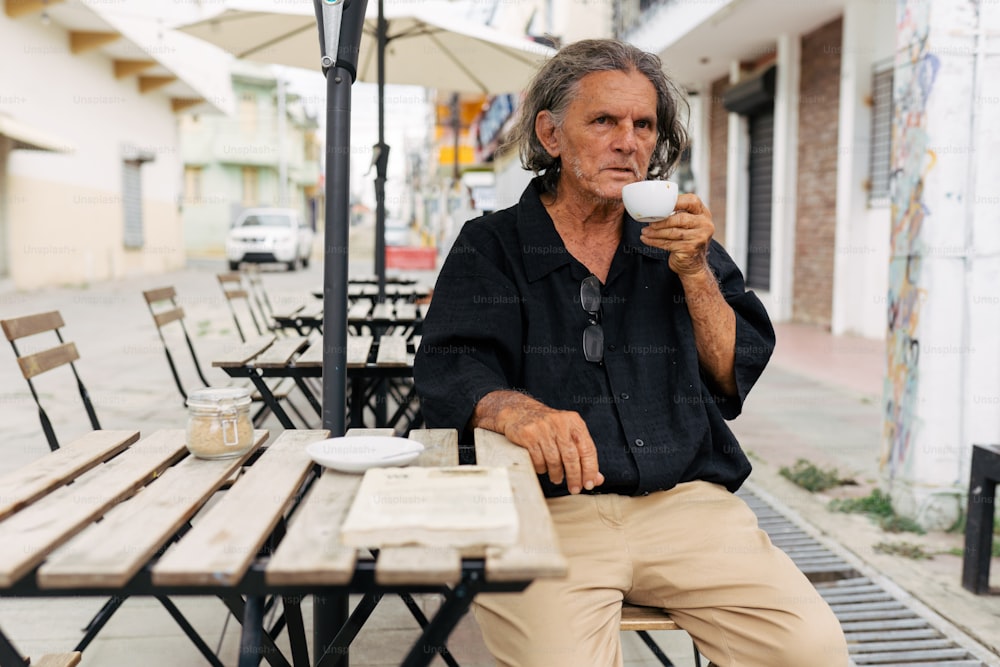 a man sitting at a table drinking a cup of coffee
