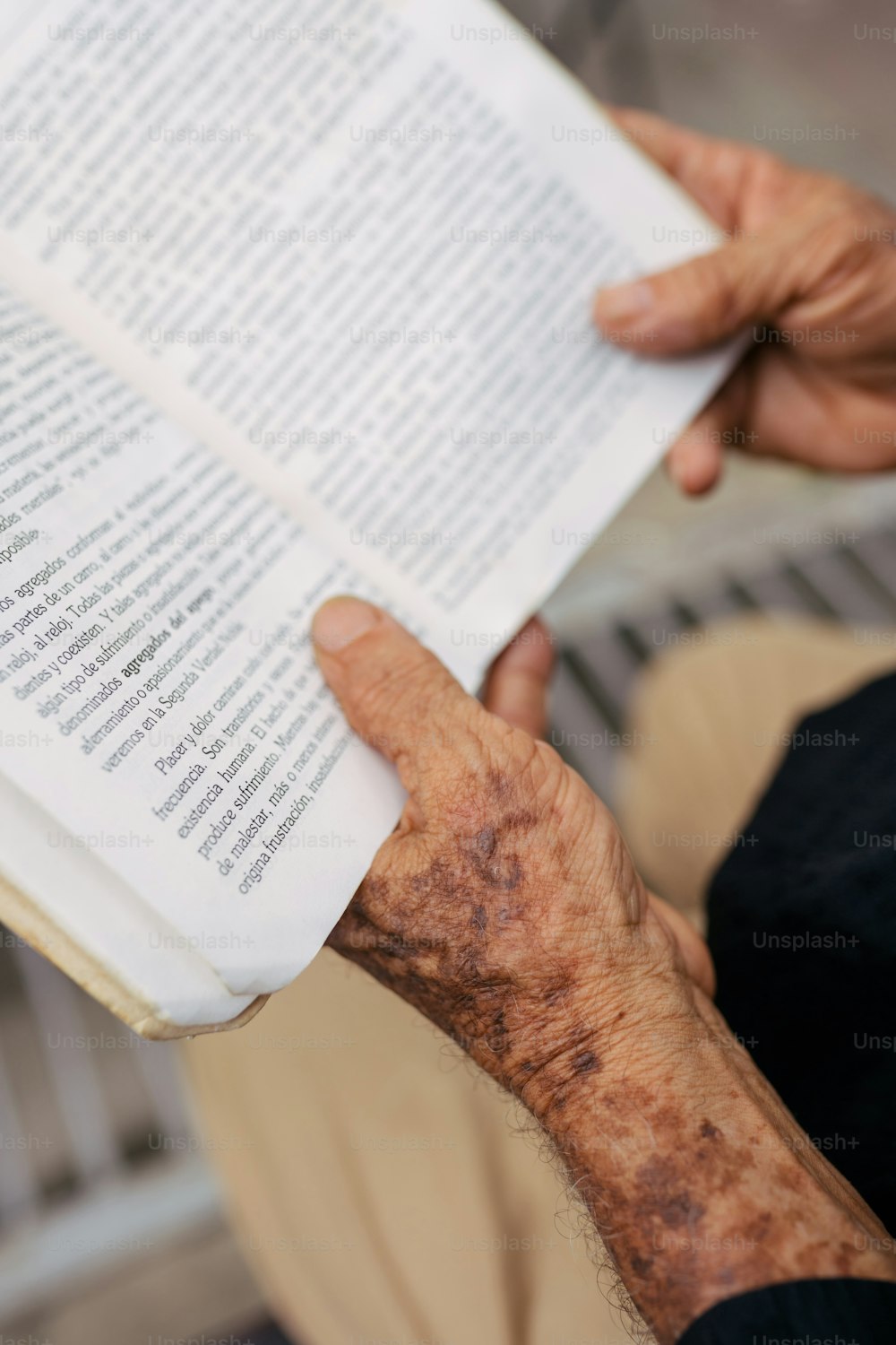 an older person holding a book open to read