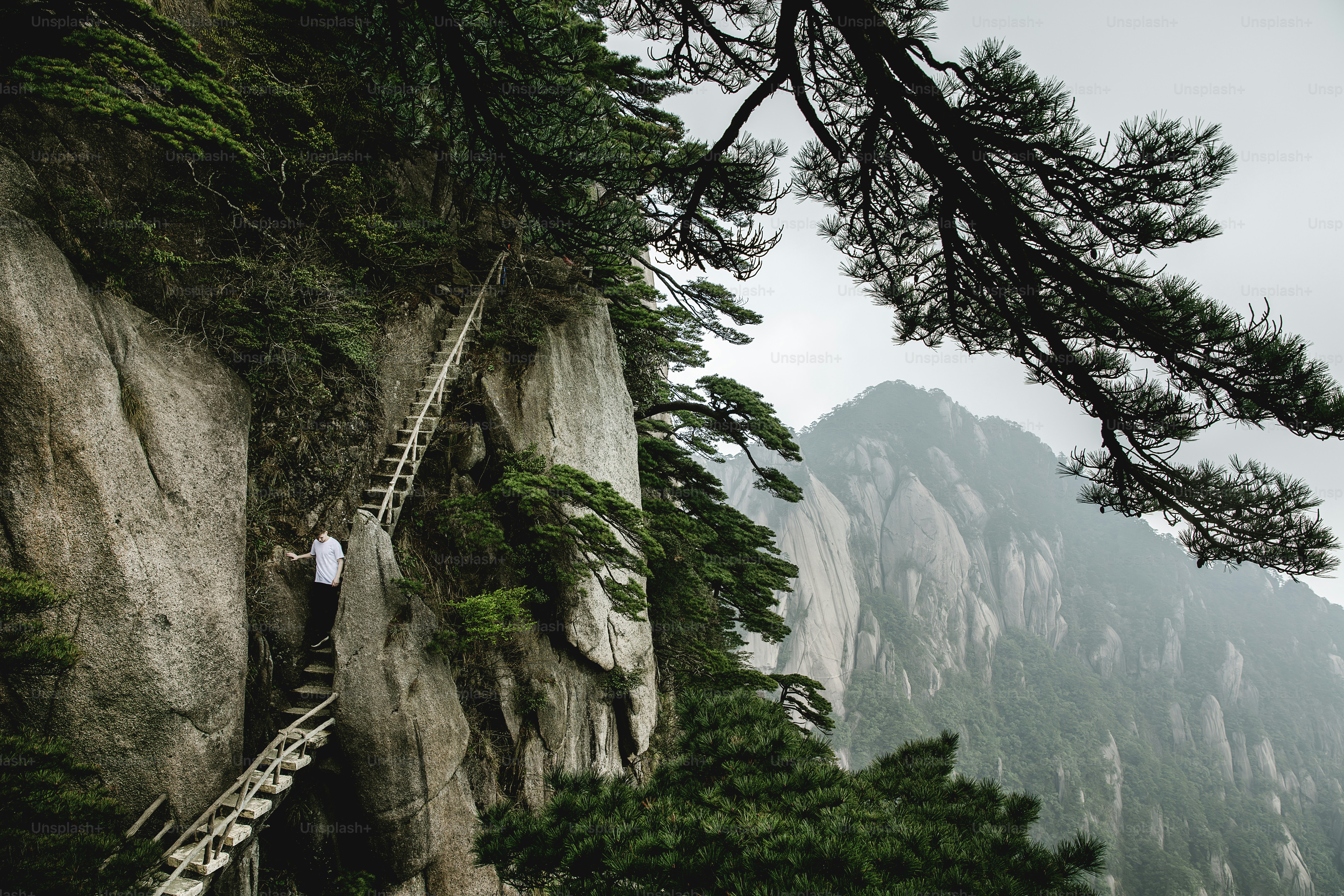 a man climbing up a steep mountain with a ladder
