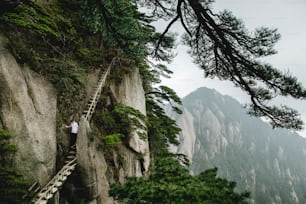 a man climbing up a steep mountain with a ladder