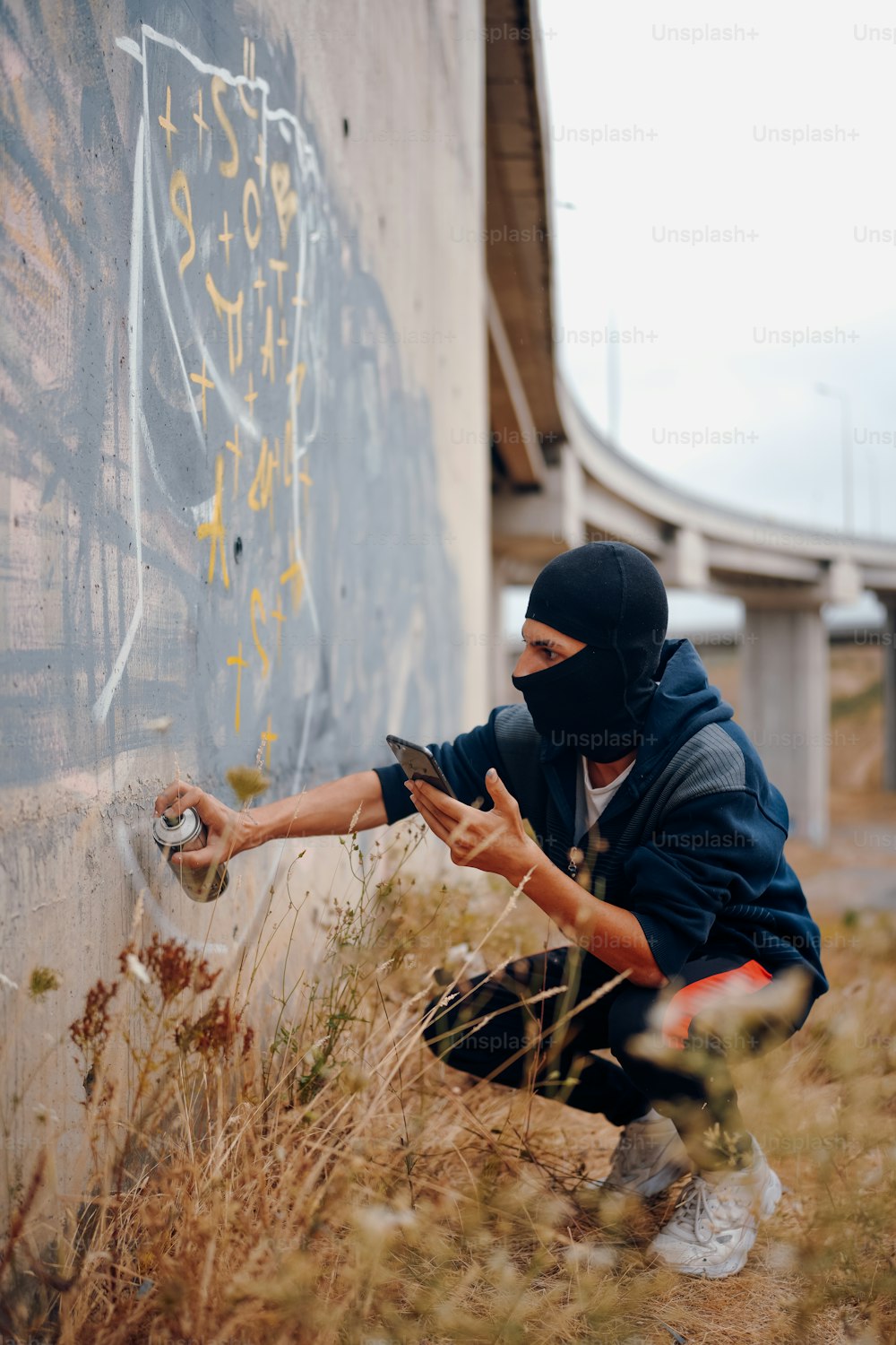 Un uomo con una maschera è appoggiato a un muro
