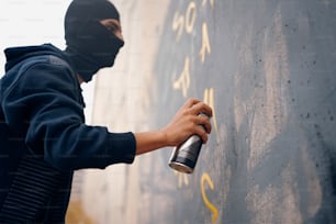 a person wearing a mask spray painting on a wall